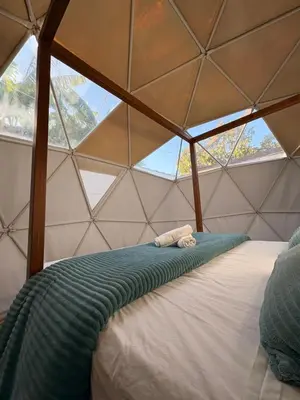 a bed in a triangular room with a window at ADAMA Glamping in Chiclana de la Frontera