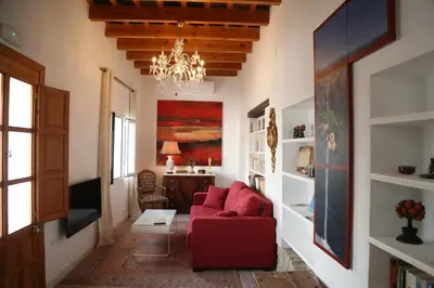 a living room with a red couch and a chandelier at Casa de la Fra in Jerez de la Frontera