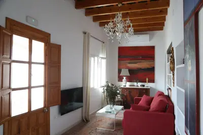 a living room with a red couch and a chandelier at Casa de la Fra in Jerez de la Frontera