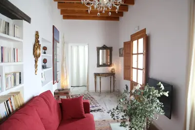 a living room with a red couch and a chandelier at Casa de la Fra in Jerez de la Frontera