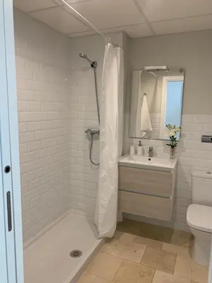 a white bathroom with a shower and a sink at Coral Oro en la Caleta Ha Apartment in Cádiz