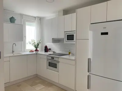 a white kitchen with white cabinets and a refrigerator at Coral Oro en la Caleta Ha Apartment in Cádiz