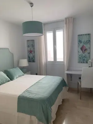 a bedroom with a bed and a desk and windows at Coral Oro en la Caleta Ha Apartment in Cádiz