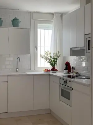 a white kitchen with white cabinets and a window at Coral Oro en la Caleta Ha Apartment in Cádiz