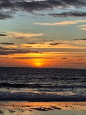 a sunset on a beach with the ocean at La Alcazaba de Cristina in El Puerto de Santa María