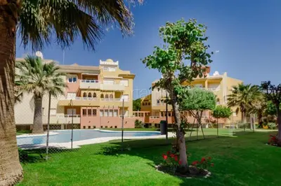 a large apartment building with a swimming pool and palm trees at La Alcazaba de Cristina in El Puerto de Santa María