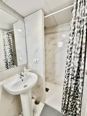 a white bathroom with a sink and a shower at Hostal Baobab in El Puerto de Santa María
