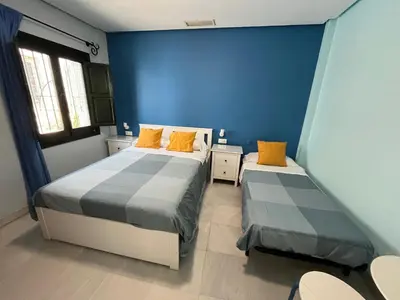 a blue room with two beds with orange pillows at Hostal Baobab in El Puerto de Santa María