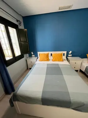a blue bedroom with a large bed with orange pillows at Hostal Baobab in El Puerto de Santa María