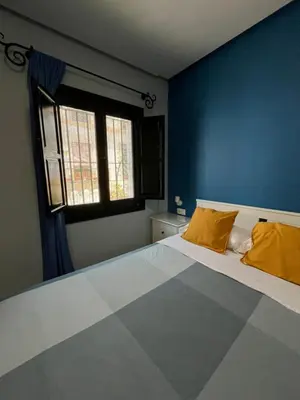 a blue bedroom with a large bed with yellow pillows at Hostal Baobab in El Puerto de Santa María