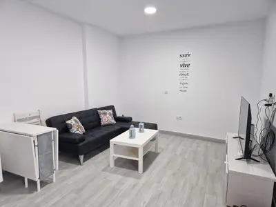 a living room with a black couch and a table at Apartamento mi currilla in Sanlúcar de Barrameda