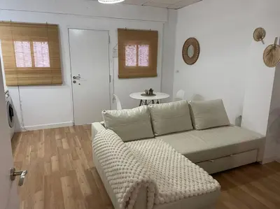 a living room with a white couch and a table at Acogedor apartamento. in Sanlúcar de Barrameda