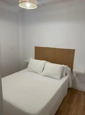 a bed with white sheets and pillows in a room at Acogedor apartamento. in Sanlúcar de Barrameda