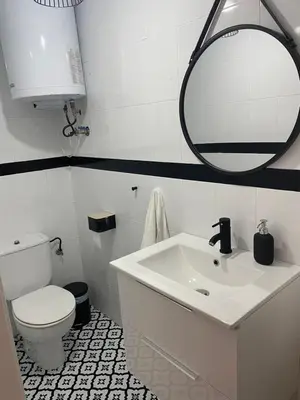 a bathroom with a sink and a toilet and a mirror at Acogedor apartamento. in Sanlúcar de Barrameda