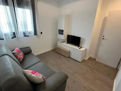 a living room with a couch and a flat screen tv at Torre D'Arenas, playa Victoria, piscina y parking in Cádiz