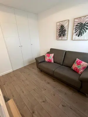 a living room with a brown couch and pink pillows at Torre D'Arenas, playa Victoria, piscina y parking in Cádiz