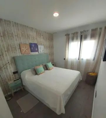 a bedroom with a large white bed with two pillows at Torre D'Arenas, playa Victoria, piscina y parking in Cádiz