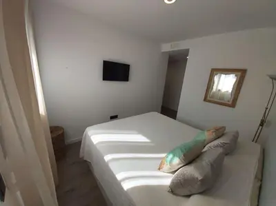 a bedroom with a white bed with pillows on it at Torre D'Arenas, playa Victoria, piscina y parking in Cádiz