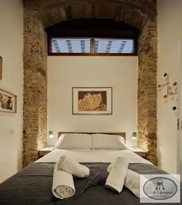 a bedroom with a large bed with brick walls at La Linda Little Apartments in Cádiz