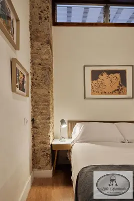 a bedroom with a bed and a brick wall at La Linda Little Apartments in Cádiz