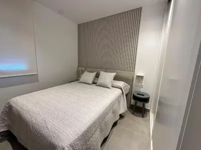 a small bedroom with a bed and a small stool at Alda & Aljosía in Chiclana de la Frontera