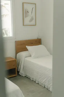 a white bedroom with a bed and a window at Alda & Aljosía in Chiclana de la Frontera