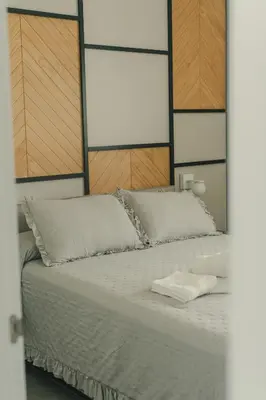 a bed with white sheets and a wooden headboard at Alda & Aljosía in Chiclana de la Frontera