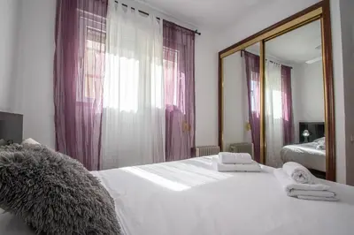 a bedroom with a large white bed and a mirror at Apartamento El descanso de Julia Augusta - Cadiz in Cádiz