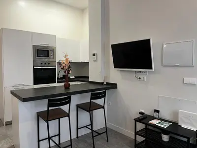 a kitchen with a counter with two stools and a tv at Kadis-Korazon Grupo AC Gestion in Cádiz