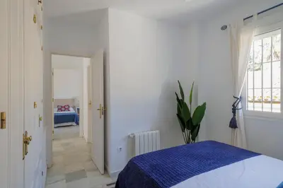 a white bedroom with a bed and a window at GINVA - Villa Puerto Sherry in El Puerto de Santa María