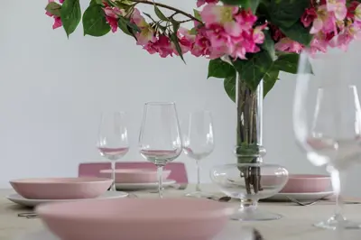a table with glasses and a vase with pink flowers at GINVA - Villa Puerto Sherry in El Puerto de Santa María
