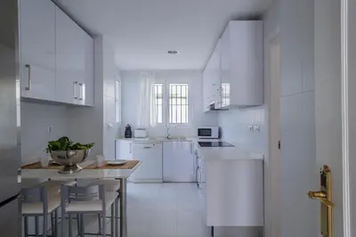 a kitchen with white appliances and a table and chairs at GINVA - Villa Puerto Sherry in El Puerto de Santa María