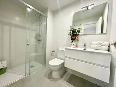 a white bathroom with a toilet and a shower at GATU PREMIUM Sandia Beach lujo junto al mar, parking y piscina común,