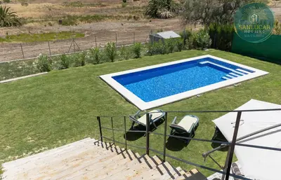 a swimming pool in a yard with two chairs and a table at Elcano Village by Sanlucar Housing in Sanlúcar de Barrameda