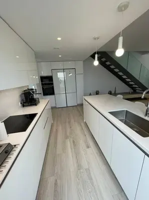 a large kitchen with white cabinets and wooden floors at Exclusivo chalet en urbanización Roche in Conil de la Frontera