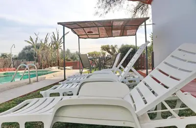 a row of white lounge chairs next to a pool at Chalet Verde Agua in Conil de la Frontera