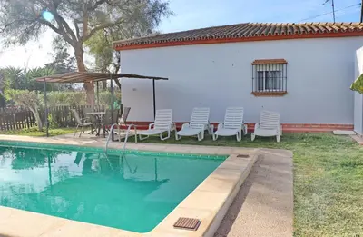 a pool with chairs and a table and an umbrella at Chalet Verde Agua in Conil de la Frontera