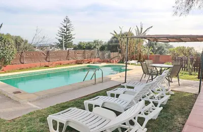 a group of white chairs and a table and a pool at Chalet Verde Agua in Conil de la Frontera