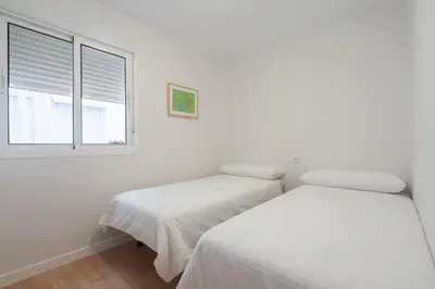 two beds in a white room with a window at Apartoyou - Plaza de Toros in El Puerto de Santa María