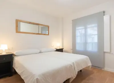 a bedroom with a large white bed and a mirror at Apartoyou - Plaza de Toros in El Puerto de Santa María