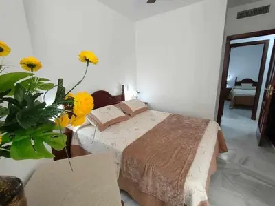 a bedroom with a bed and a vase of flowers at Casita de la Infanta by Sanlúcar Housing in Sanlúcar de Barrameda