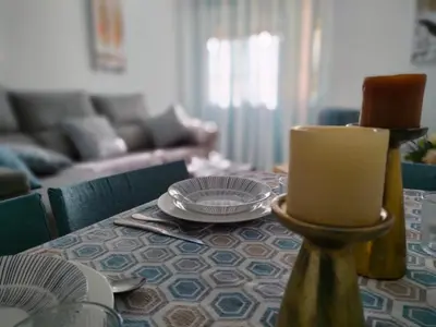 a dining room table with a candle and a couch at Casita de la Infanta by Sanlúcar Housing in Sanlúcar de Barrameda