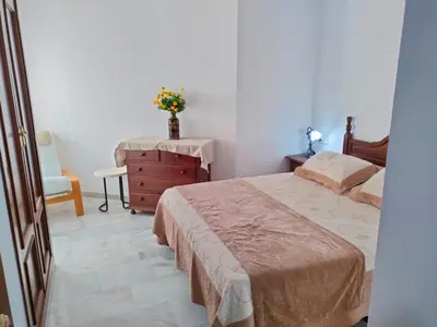 a bedroom with a bed and a dresser with a vase on it at Casita de la Infanta by Sanlúcar Housing in Sanlúcar de Barrameda