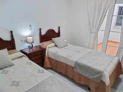 a bedroom with two beds and a window at Casita de la Infanta by Sanlúcar Housing in Sanlúcar de Barrameda