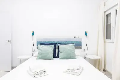 a white bed with a blue headboard and two pillows at La Casa del Mercader by Gades Gestión in Cádiz