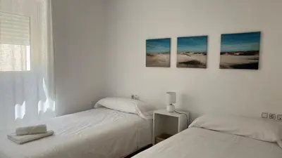 two beds in a white bedroom with three pictures on the wall at Luz Baal Grupo AC Gestion in Cádiz
