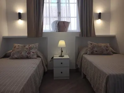 a bedroom with two beds and a table with a lamp at APARTAMENTOS LUZ DE LA BAHÍA SUR CADIZ San Fernando in San Fernando