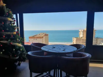 a table with chairs and a christmas tree in front of a window at El vigía de cadiz in Cádiz