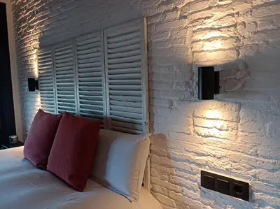 a bedroom with a brick wall and a bed with a red pillow at El vigía de cadiz in Cádiz