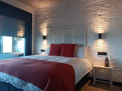 a bedroom with a large bed and a brick wall at El vigía de cadiz in Cádiz
